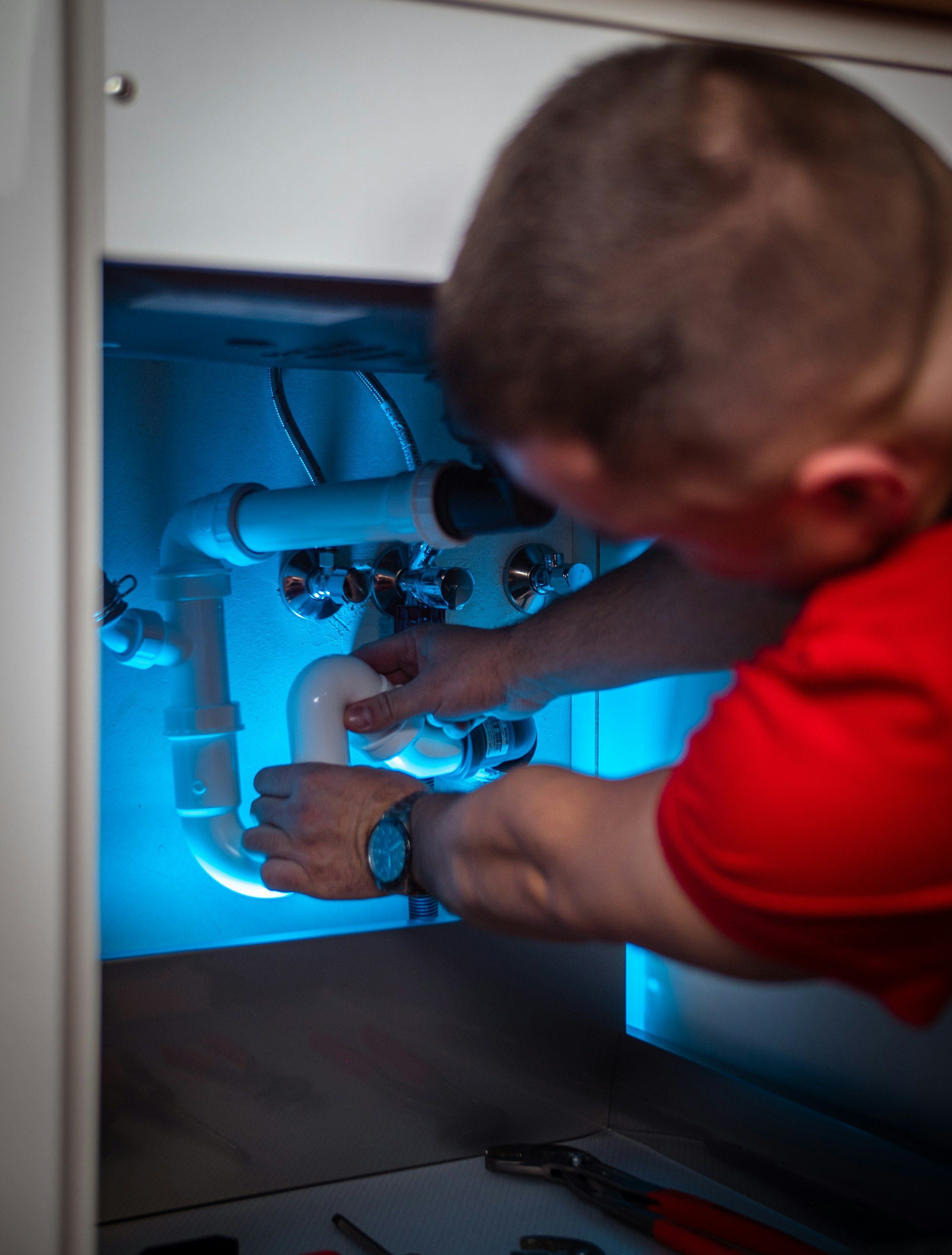 Installateur montiert Rohrleitungen unter einem Waschtisch