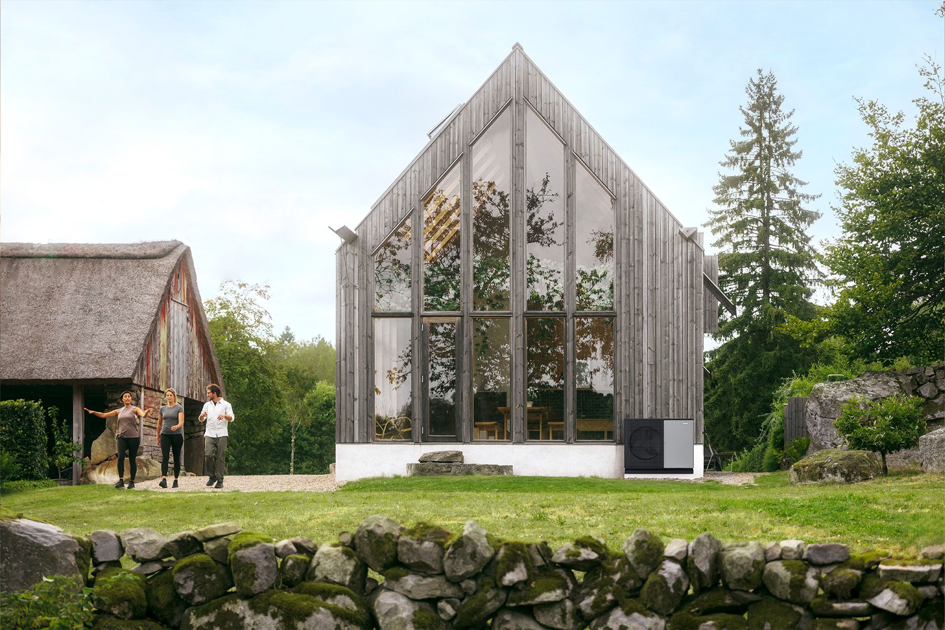 Modernes Holzhaus mit großer Glasfront im Grünen, davor die Außeneinheit einer Wärmepumpe